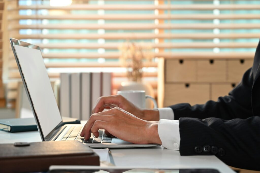 Side view of businessman hands typing on laptop keyboard, searching information.